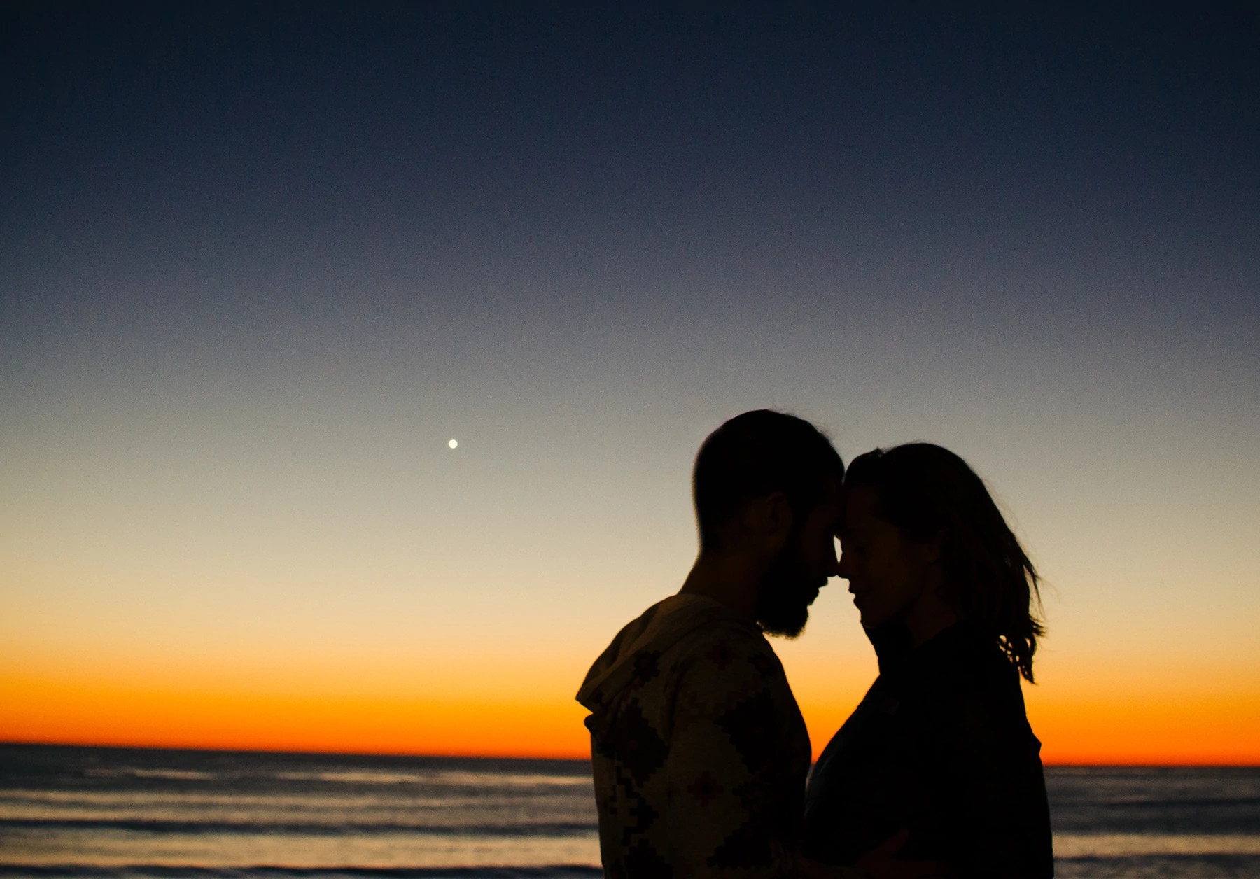 couple embracing in front of sunset