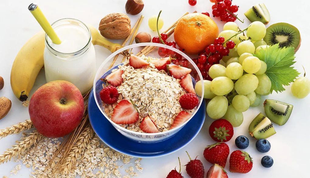 Eating healthy is one of the six pillars of brain health A close-up view of a bowl of muesli surrounded by fruits and a glass of milk