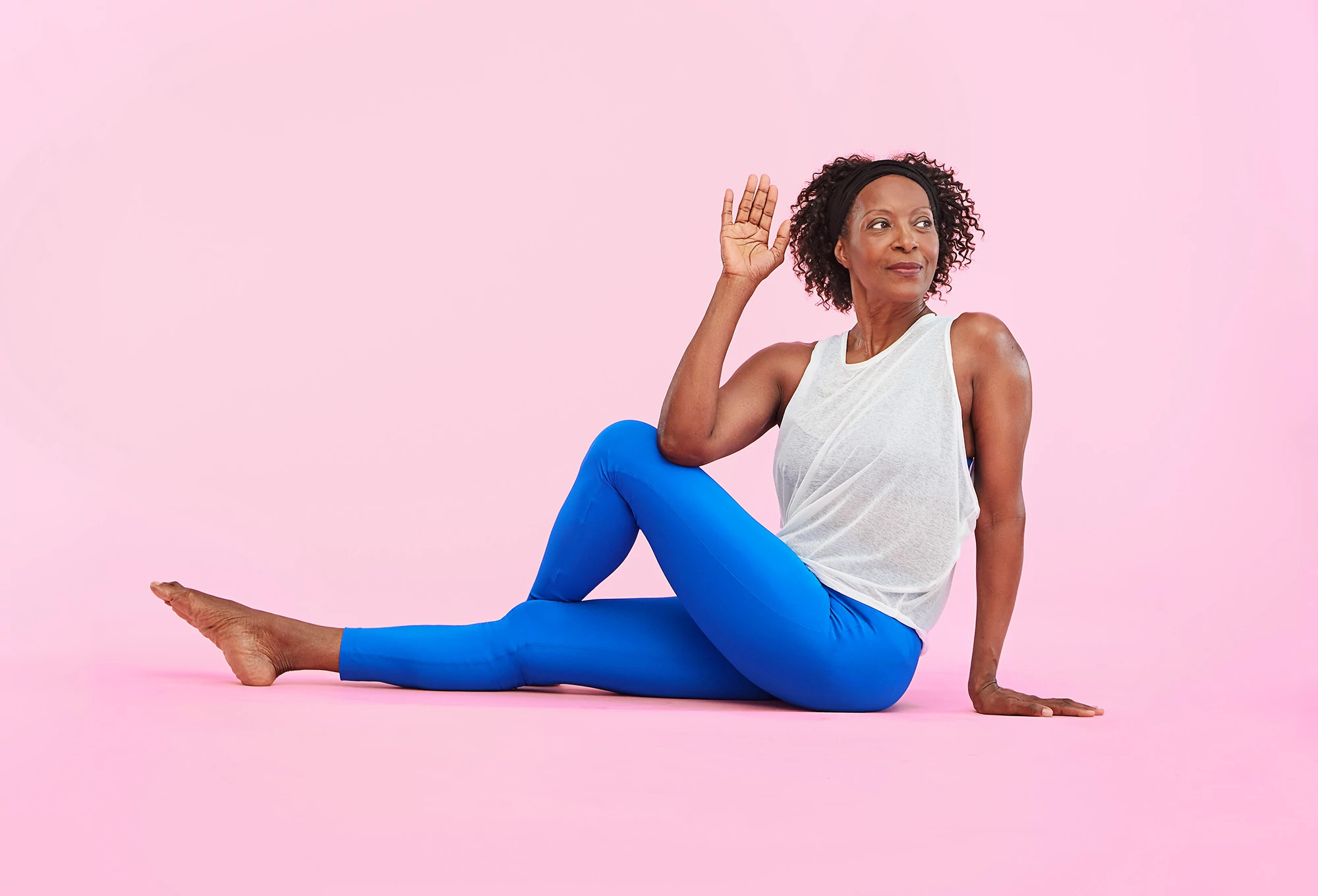 african american woman wearing athletic clothes stretching with yoga on a pink background