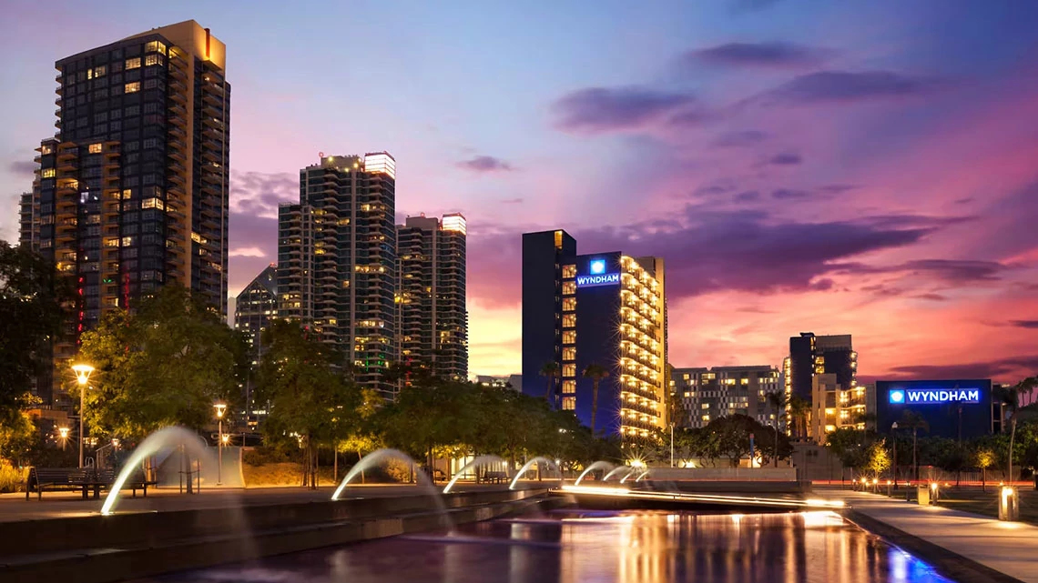 Wyndham Hotels & Resorts outdoor fountain with multiple hotels in the background, sunset, city lights on