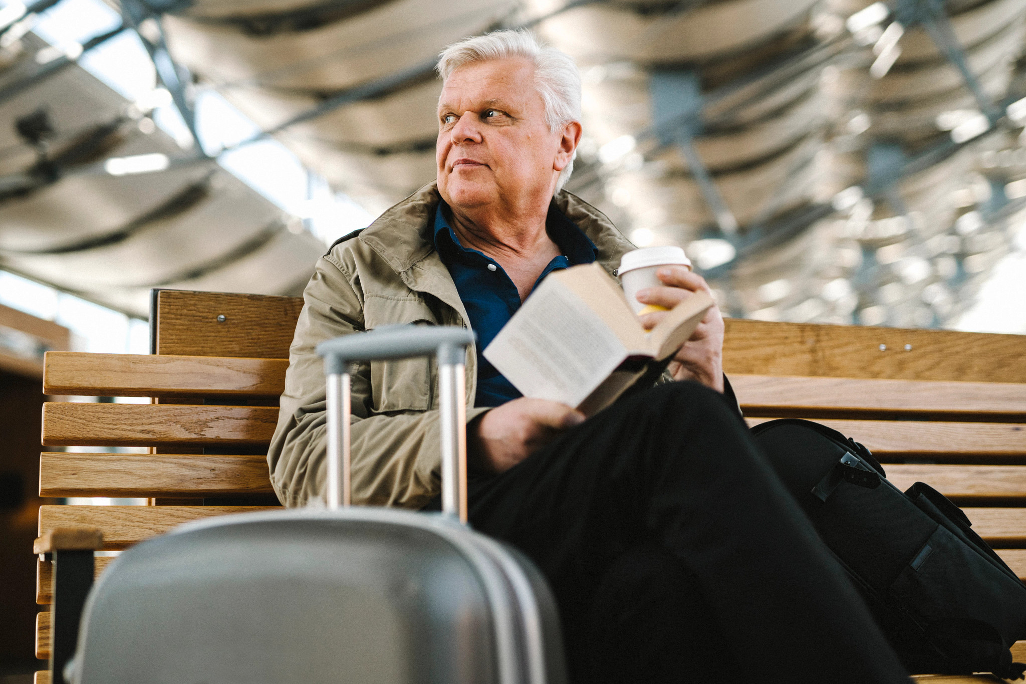 older man with luggage and book at airport
