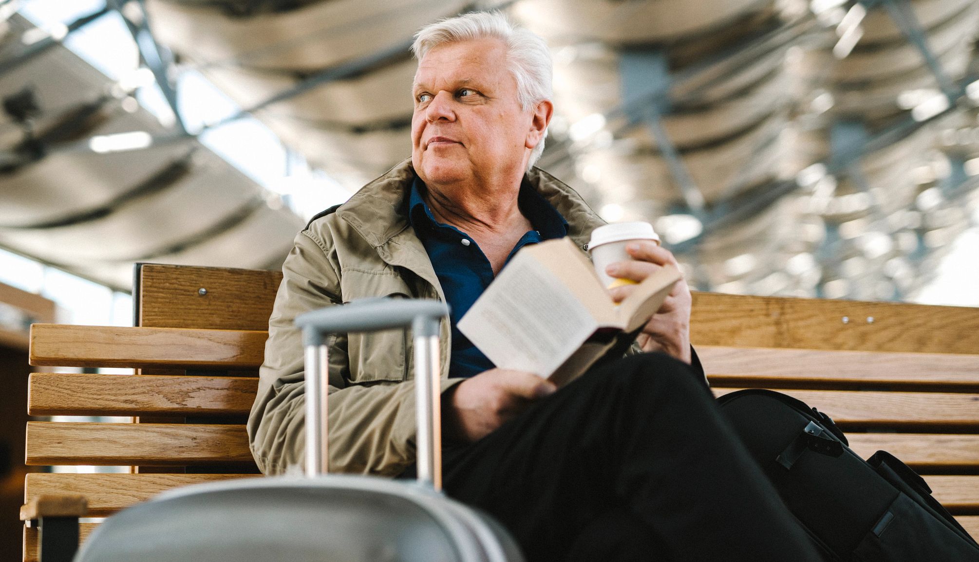 older man with luggage and book at airport