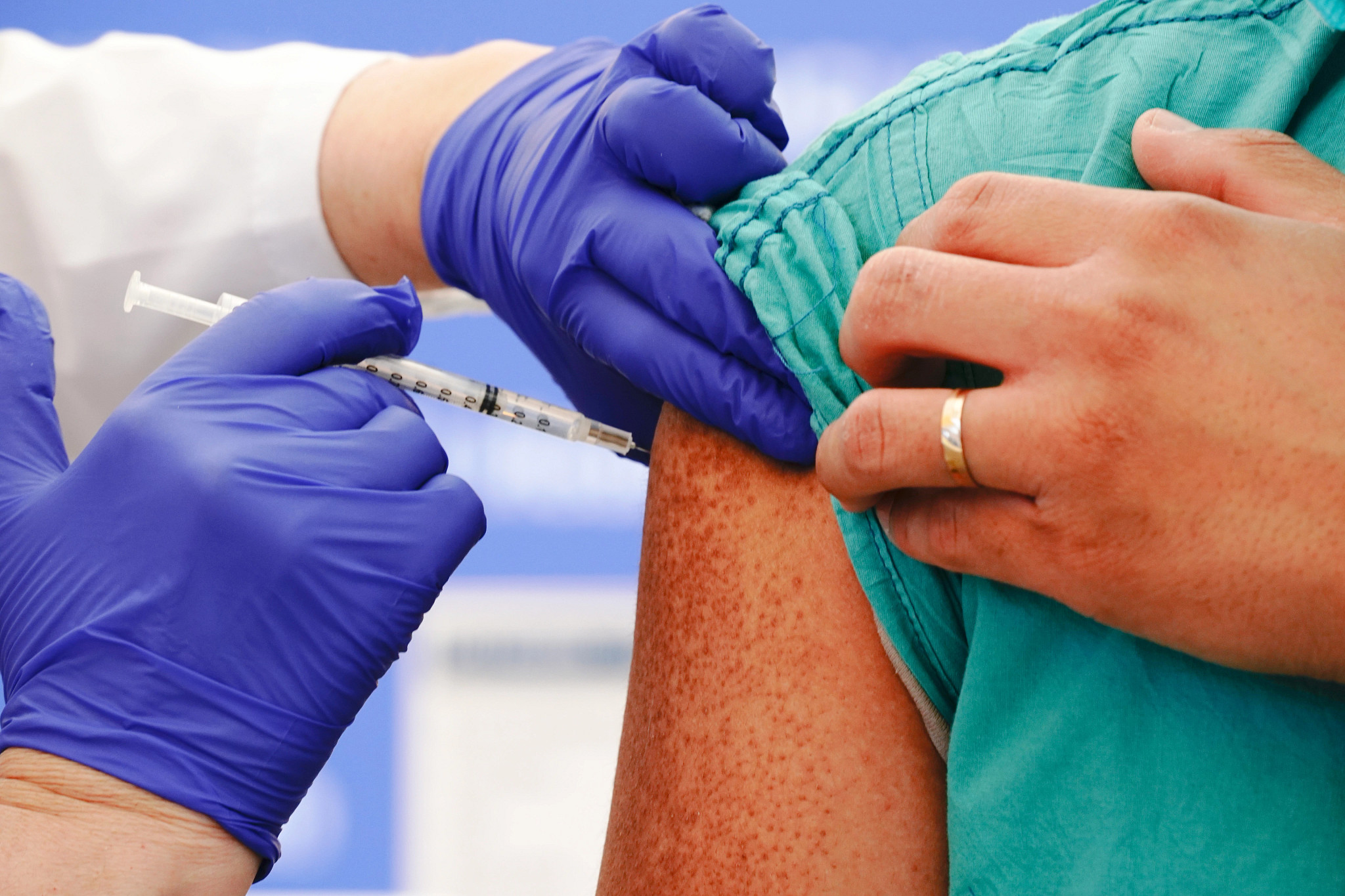 A healthcare provider gives an adult a COVID vaccine shot in the upper arm.