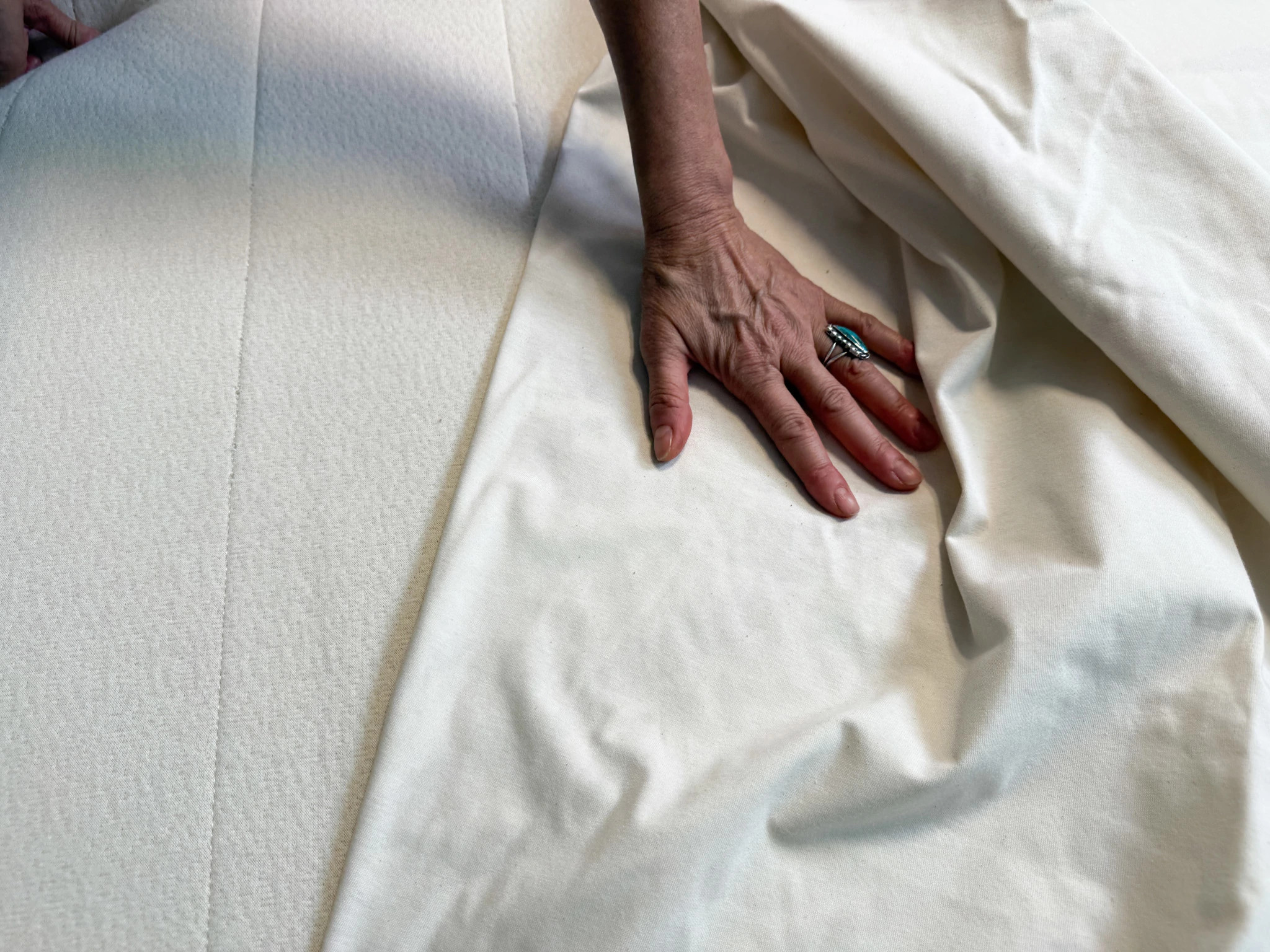 A woman’s hand touching the Birch Waterproof Mattress Protector.