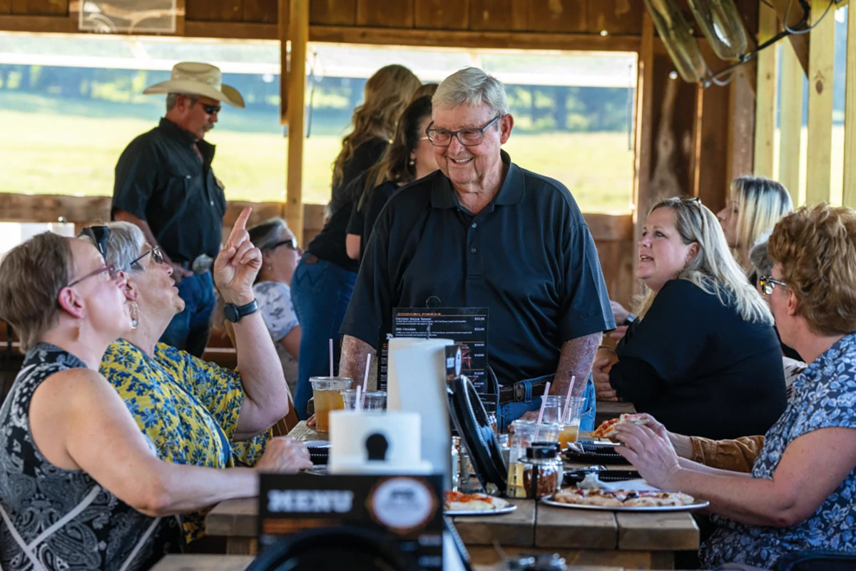 people talking and eating while sitting at a table