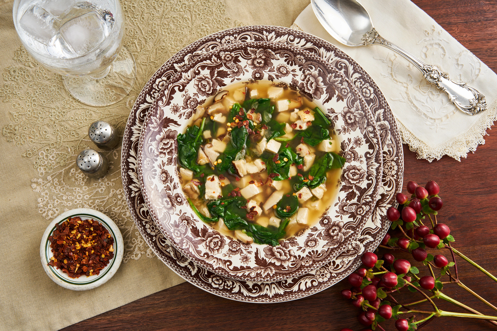 Holiday soup with spinach and white beans served in an ornate brown bowl on a festive table