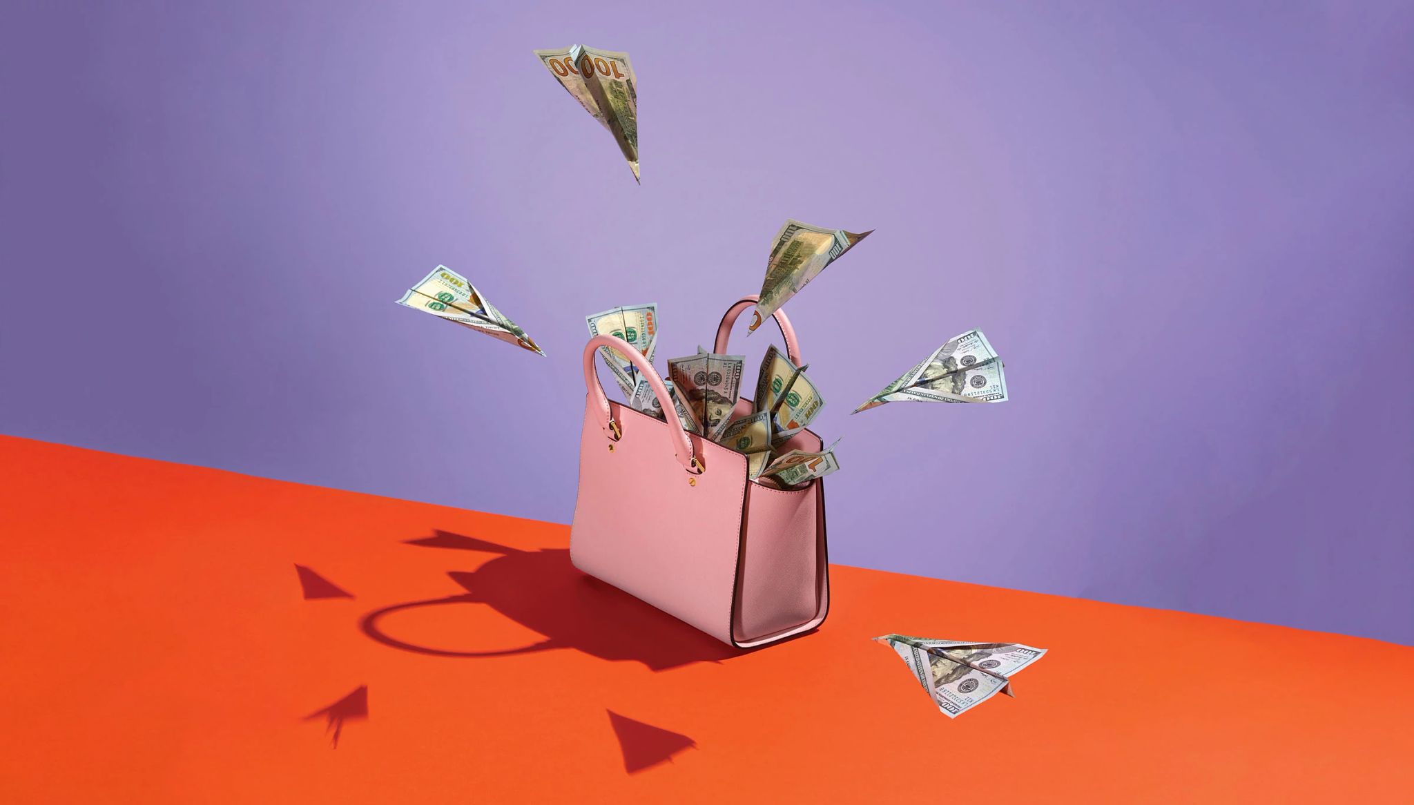 pink purse with hundred dollar bills folded as airplanes inside and outside of it