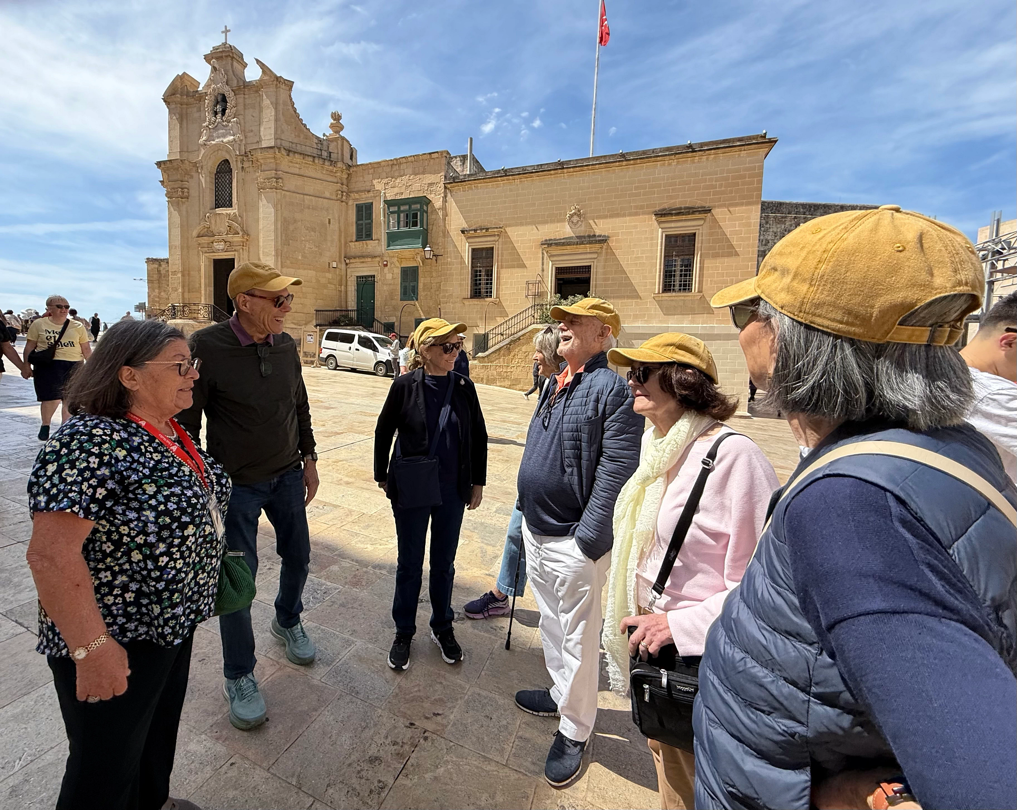 a group of people talking and laughing outside a building in malta