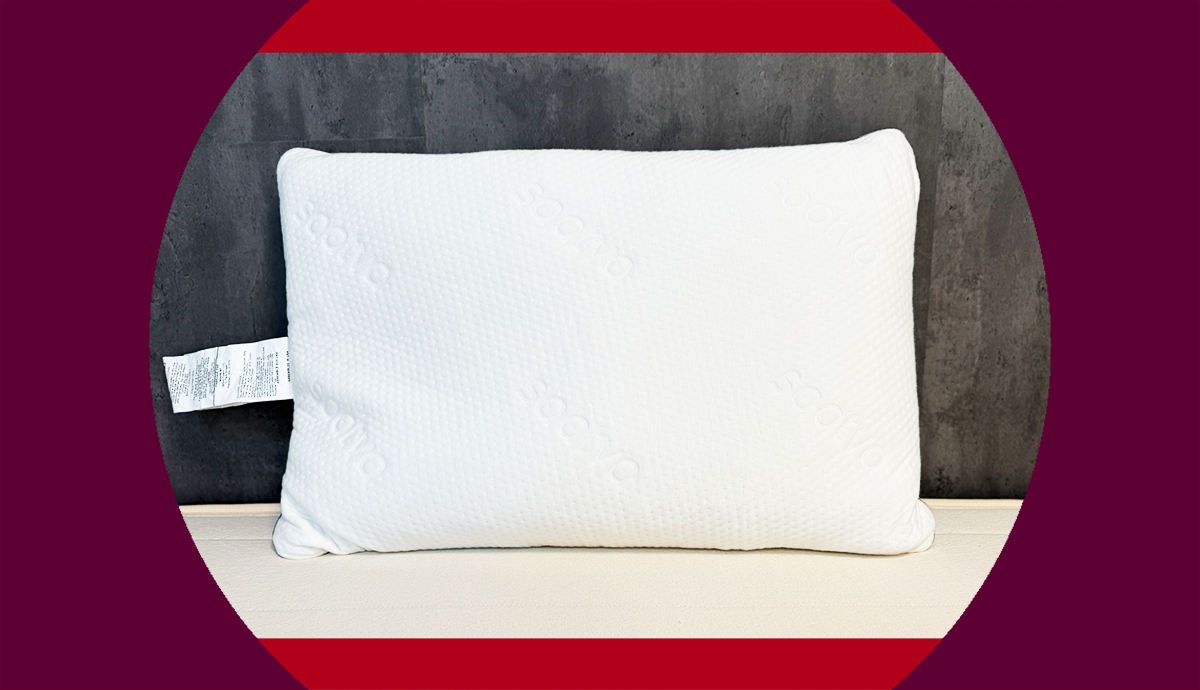 The Saatva Graphite Memory Pillow propped up on a dark gray wall