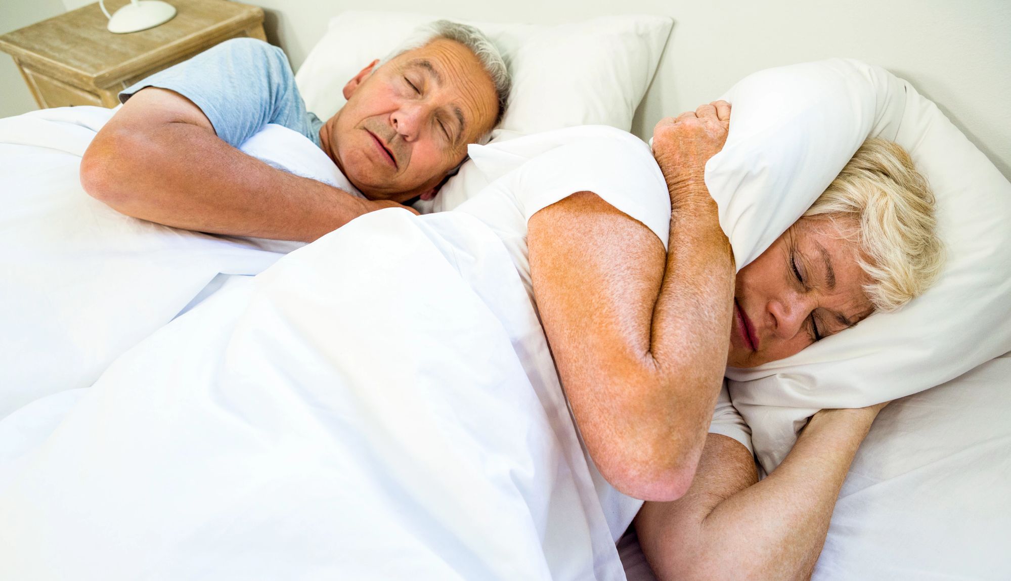 Snoring High angle view of woman sleeping by snoring man on bed at home