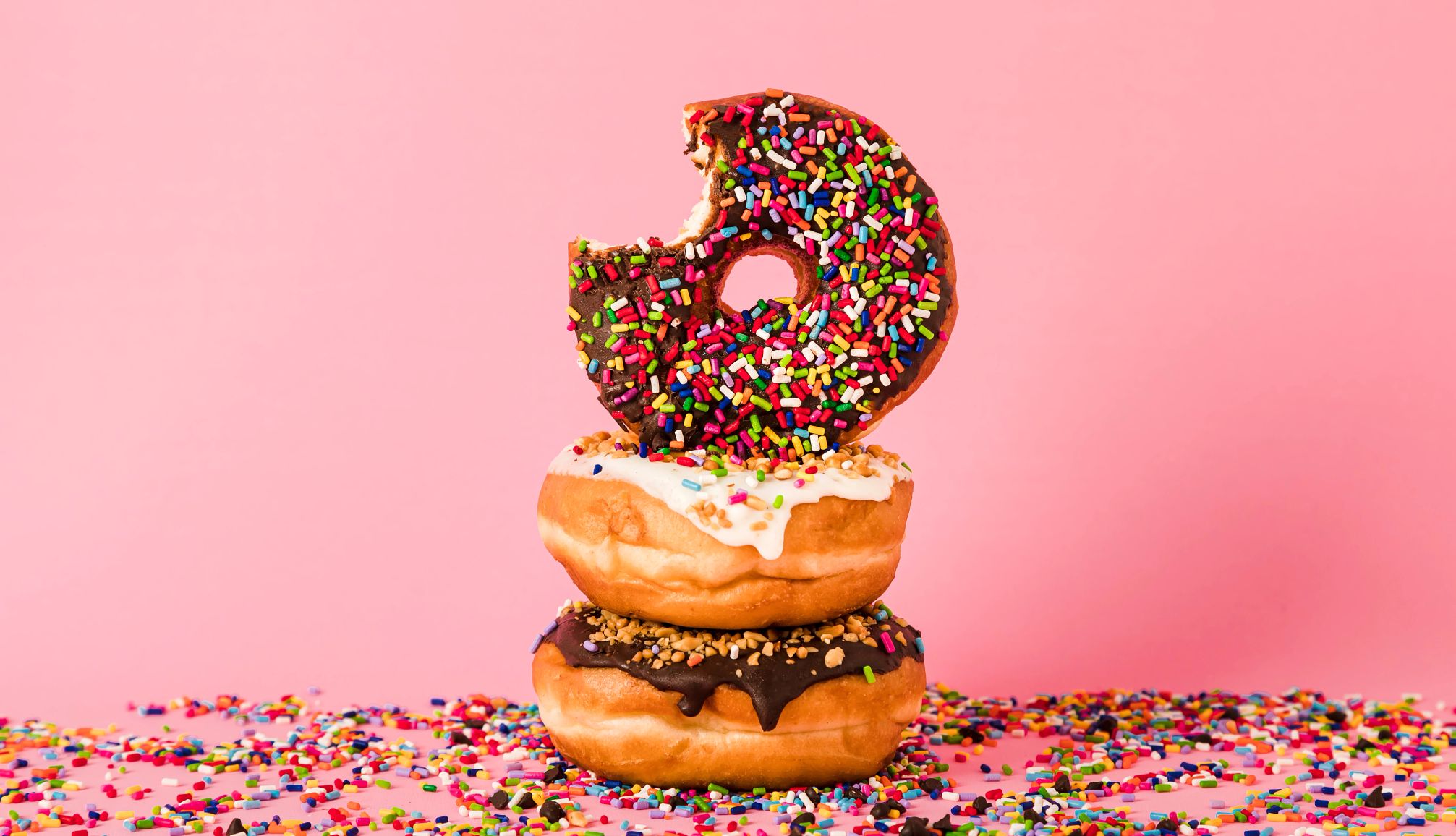 National Donut Day deals an assortment of donuts on a pink background