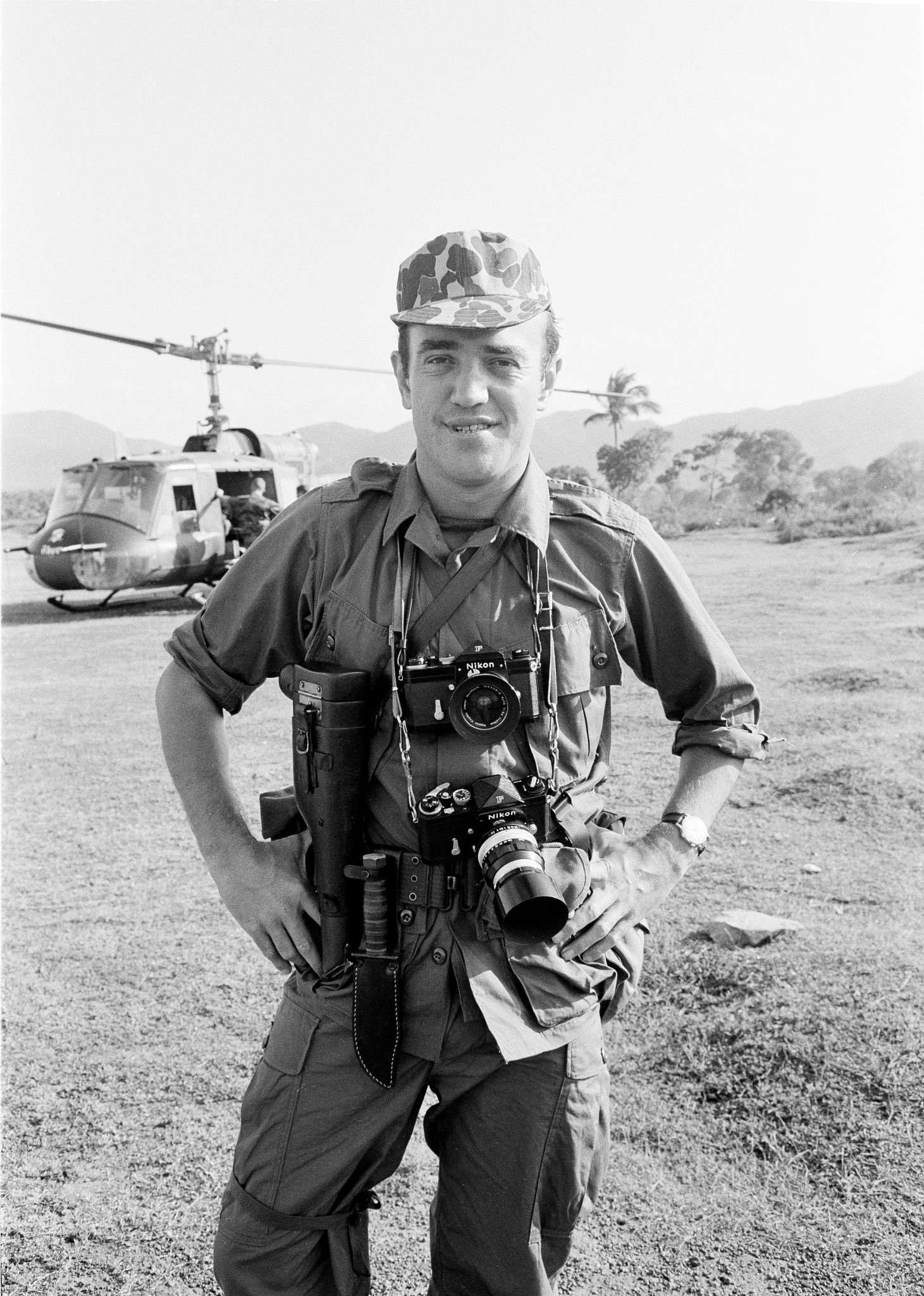 journalist peter arnett in military gear with cameras posing in vietnam