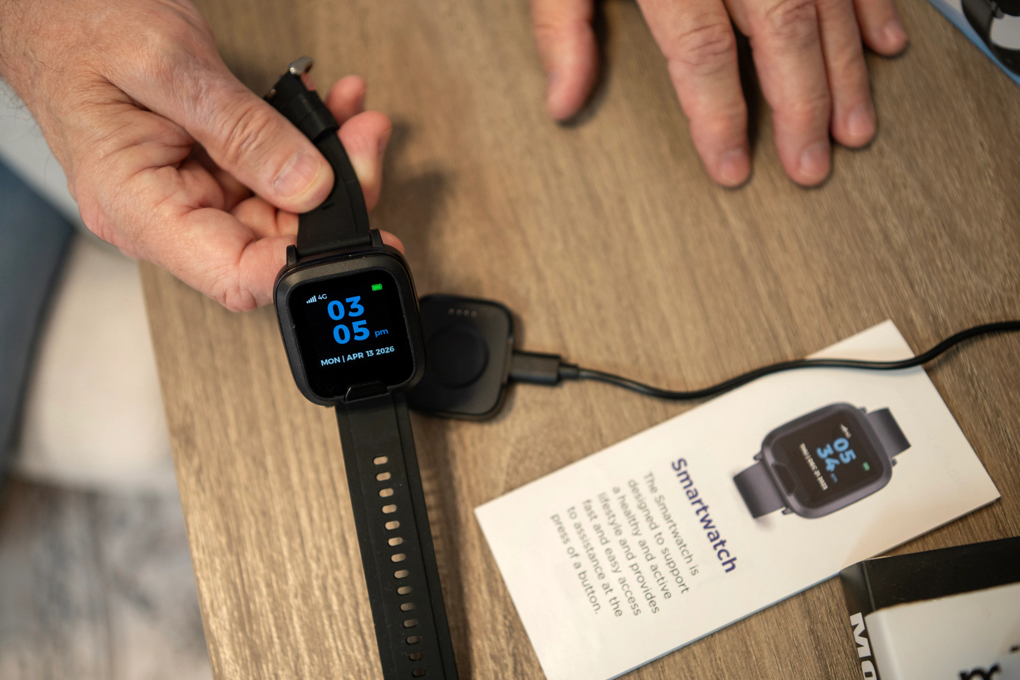 A man putting the Lifeline Smartwatch on its charger.