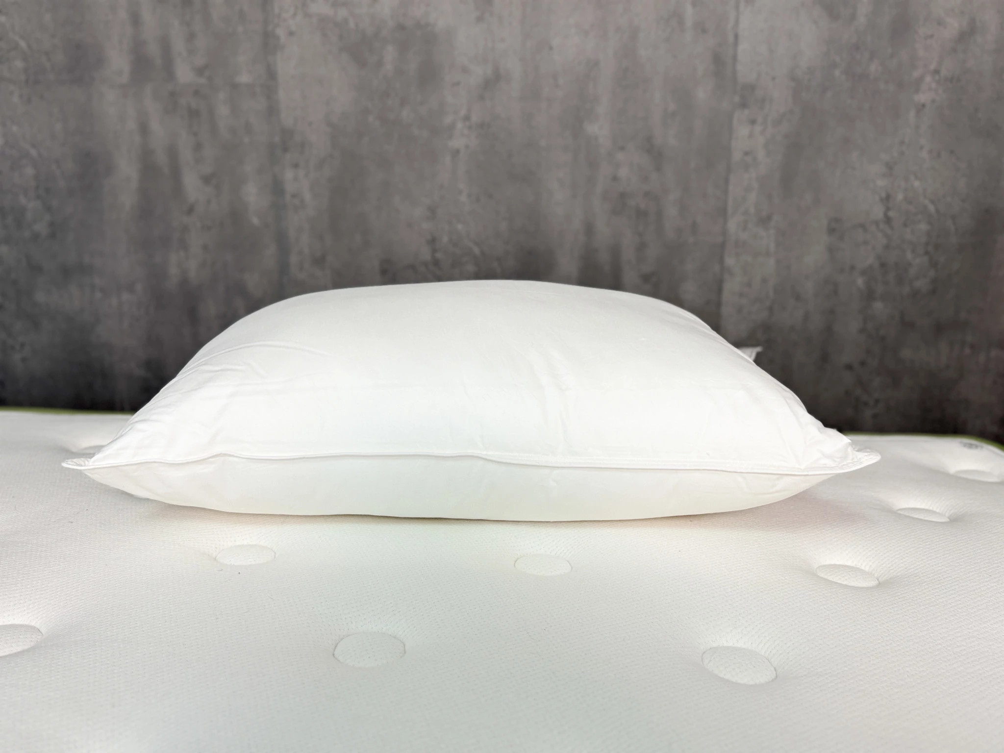 The Quince Premium Down Alternative Pillow on a mattress