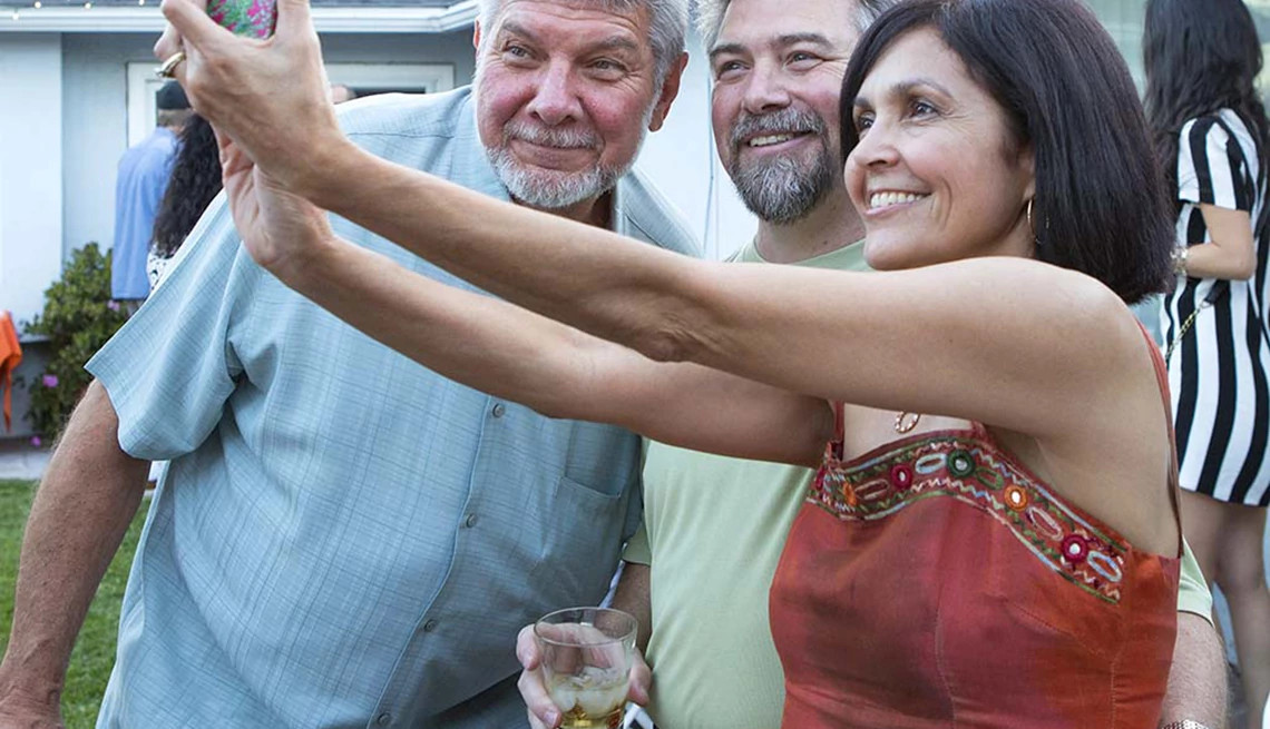 A woman taking a selfie with two men outside