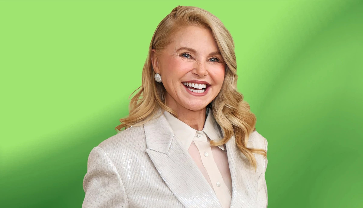 Christie Brinkley smiling in a white sequined jacket and white blouse