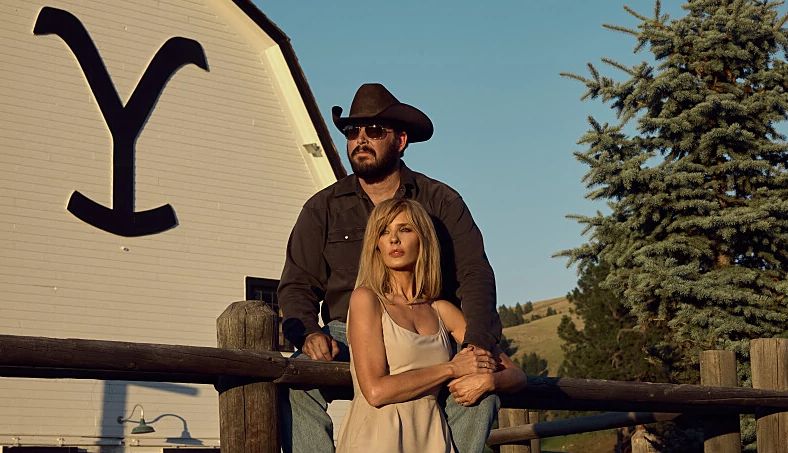 Rip and Beth from Yellostone a man and woman posing in front of a barn