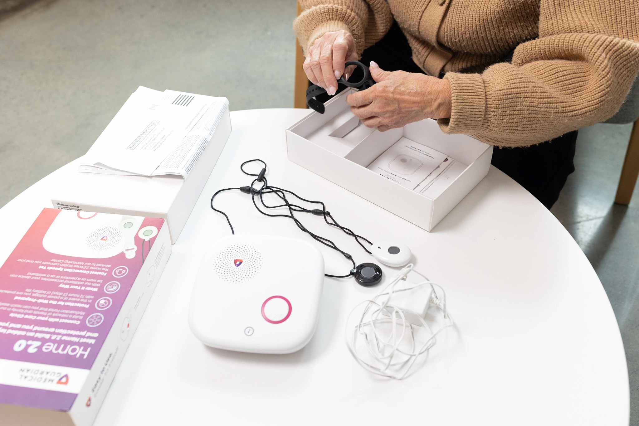 A woman unboxes the MG Home 2.0 medical alert system and puts it on a table