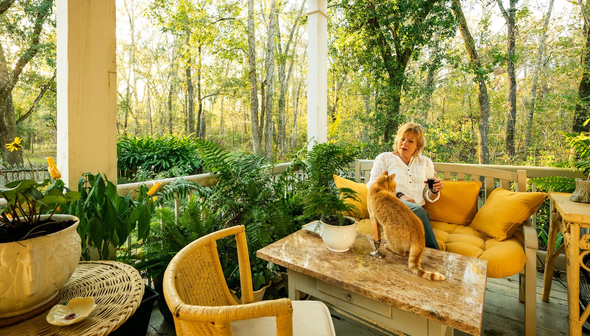 blond woman relaxes on the porch and pets a cat