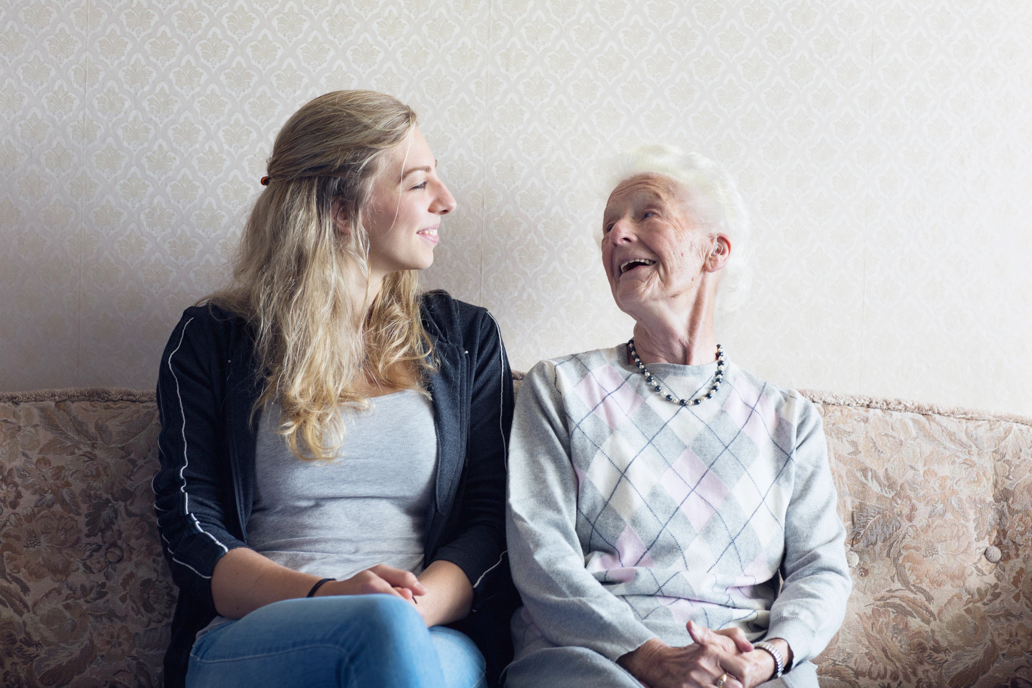 caregiver and woman sitting on a sofa, laughing