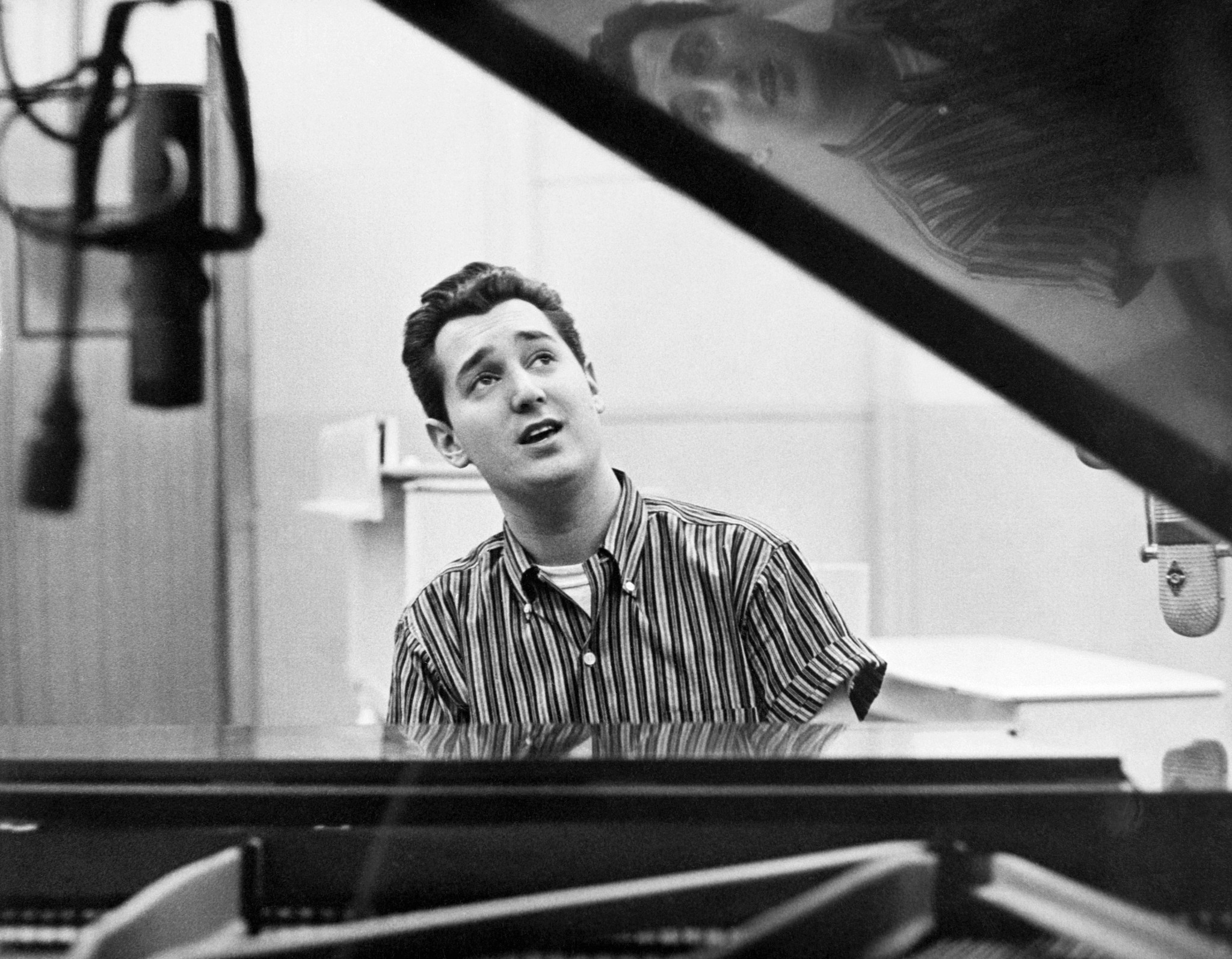 neil sedaka seated at a piano in a black and white photo 