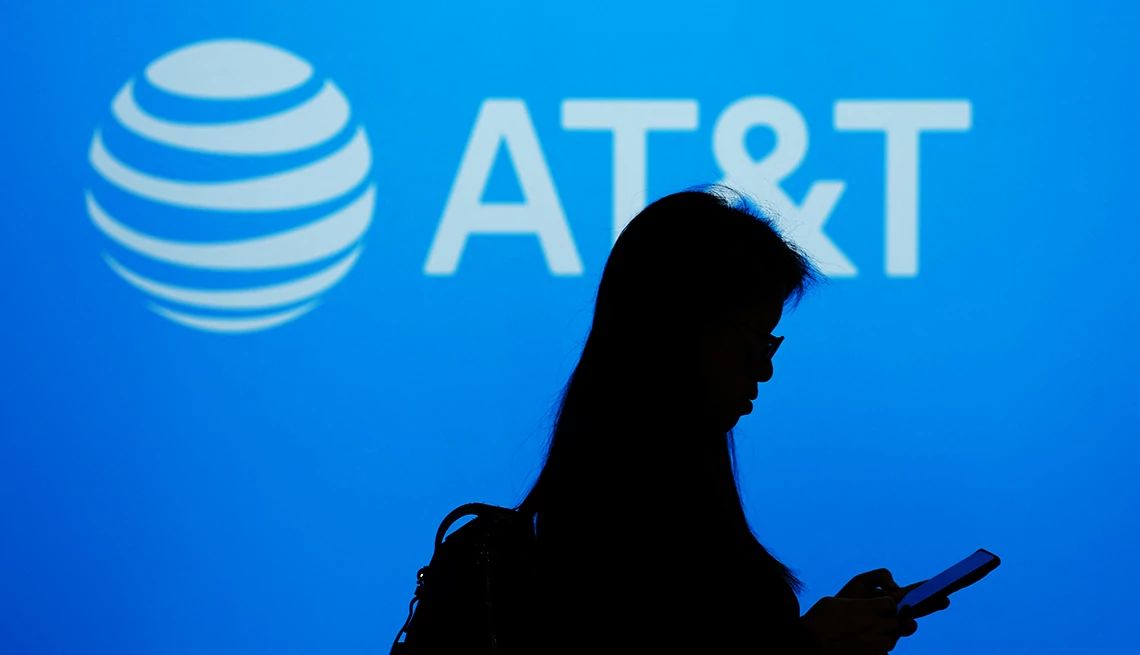 What You Need to Know About the AT&T Data Breach a person is walking in front of a blue sign that says a t and t