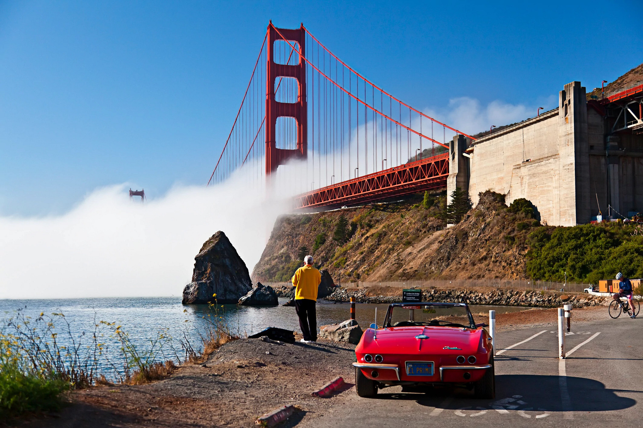 a person standing next to a car with the Golden Gate Bridge in the background