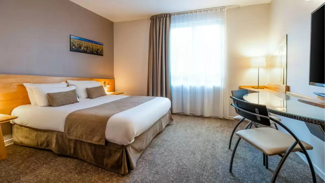 Quality Inn® guestroom hotel with bed, desk, window, neutral colors