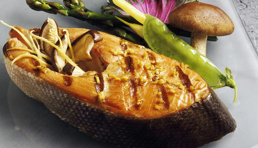 People who eat fish report having better brain health A close-up view of grilled salmon steak with mushrooms, asparagus, snow peas and beans