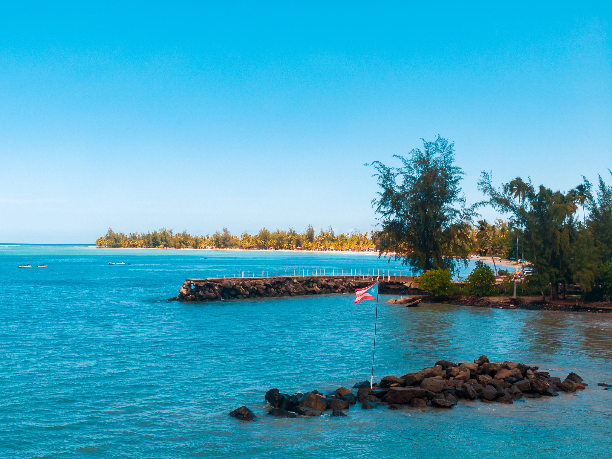the puerto rican flag erected in the water off the shore of a beach