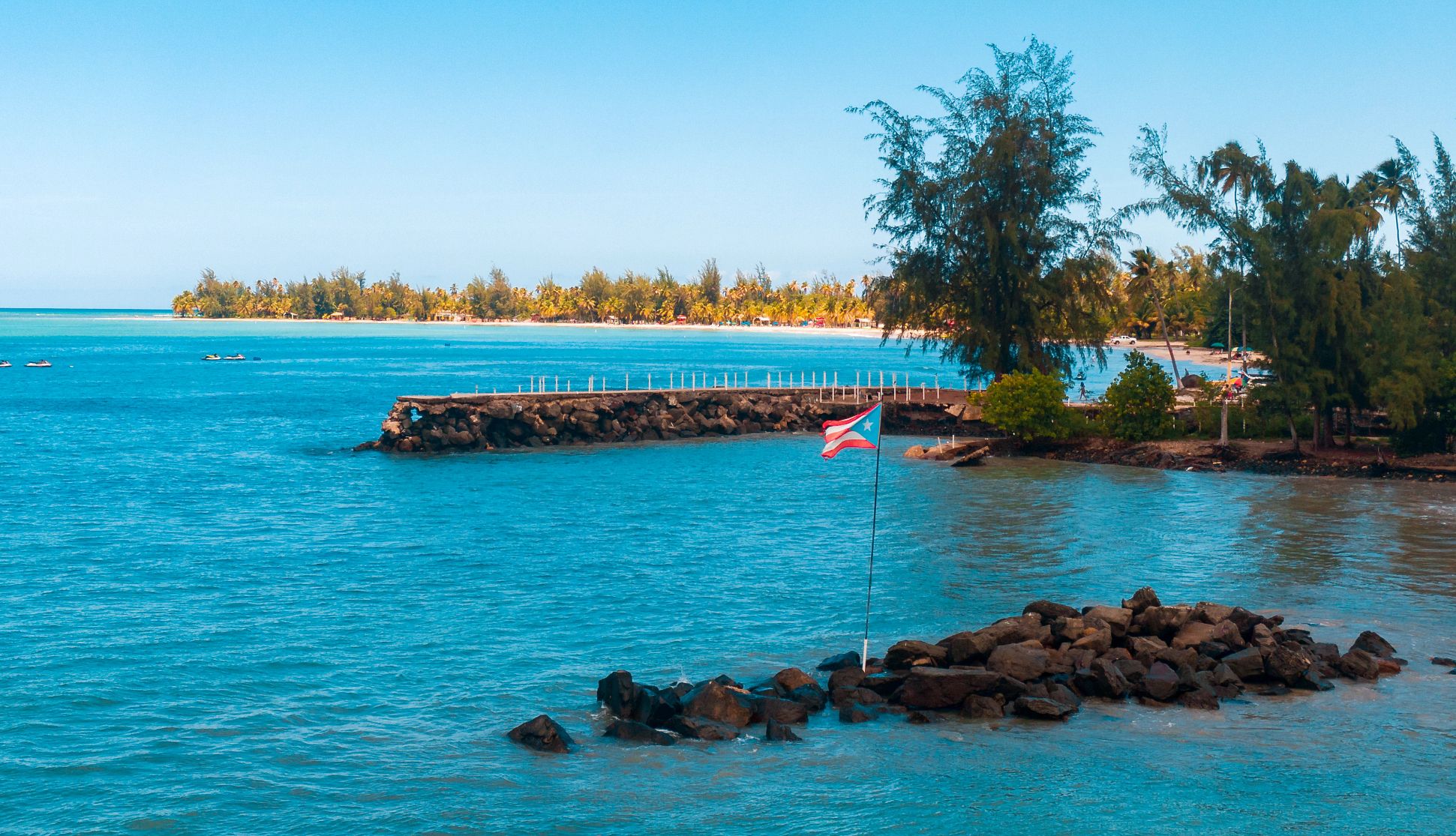 Quiet Caribbean Beaches the puerto rican flag erected in the water off the shore of a beach