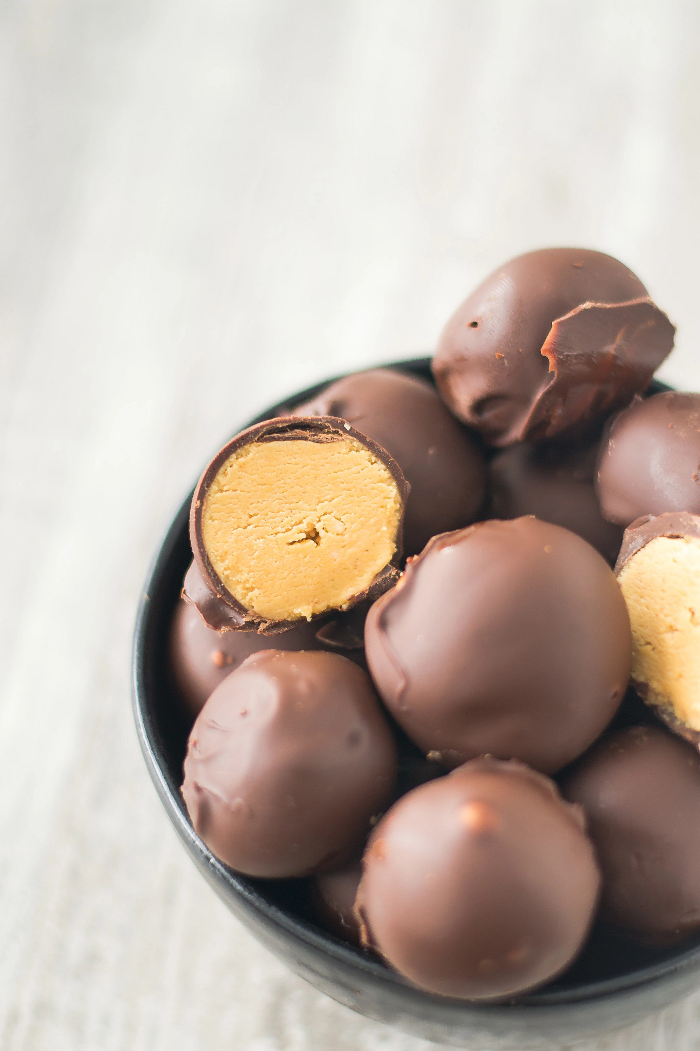 Close-up of Peanut Butter Cup Cottage Cheese Balls in a bowl, with one piece cut open to reveal a creamy filling