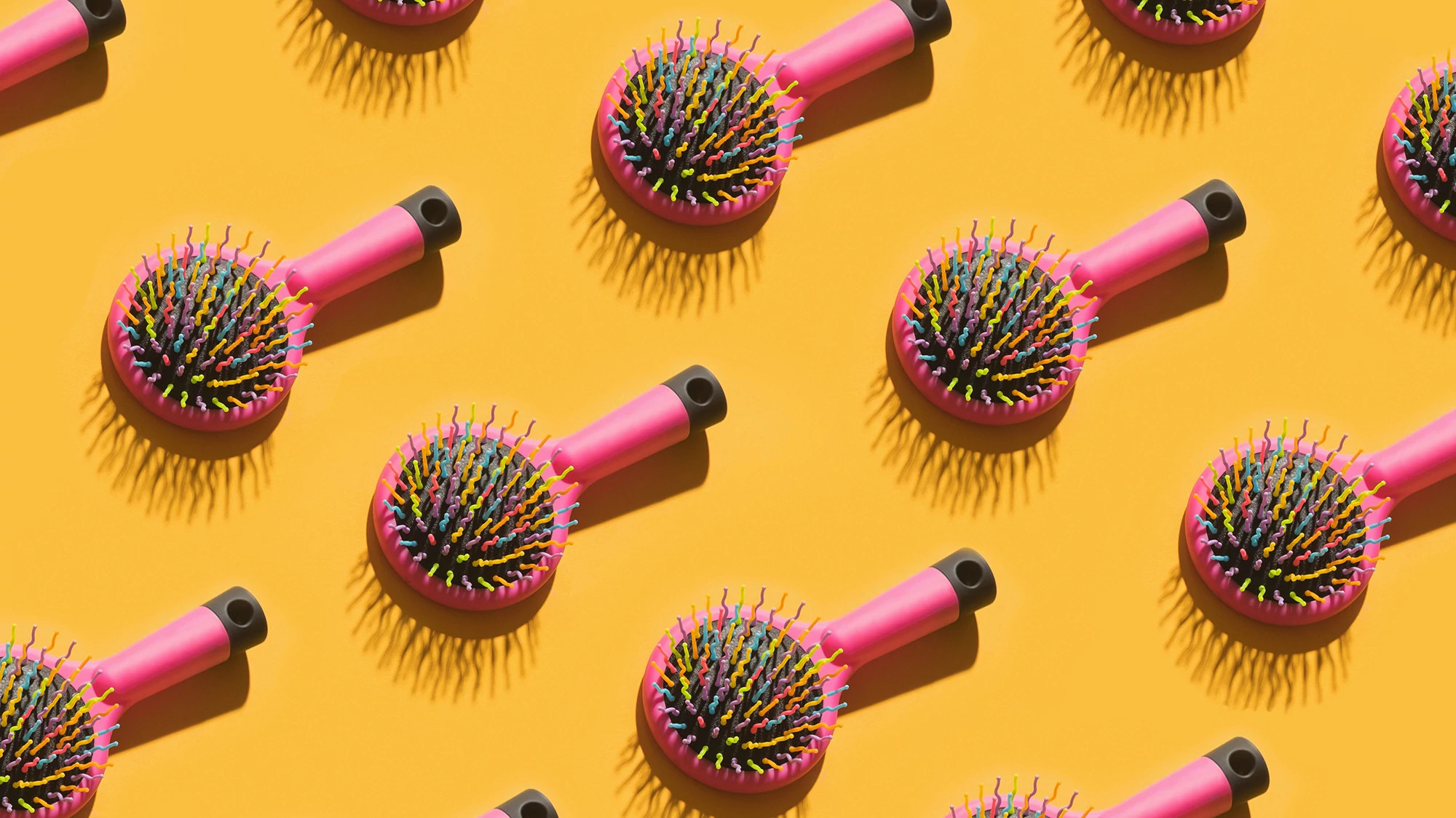 Repeating pink hair brushes casting shadows 