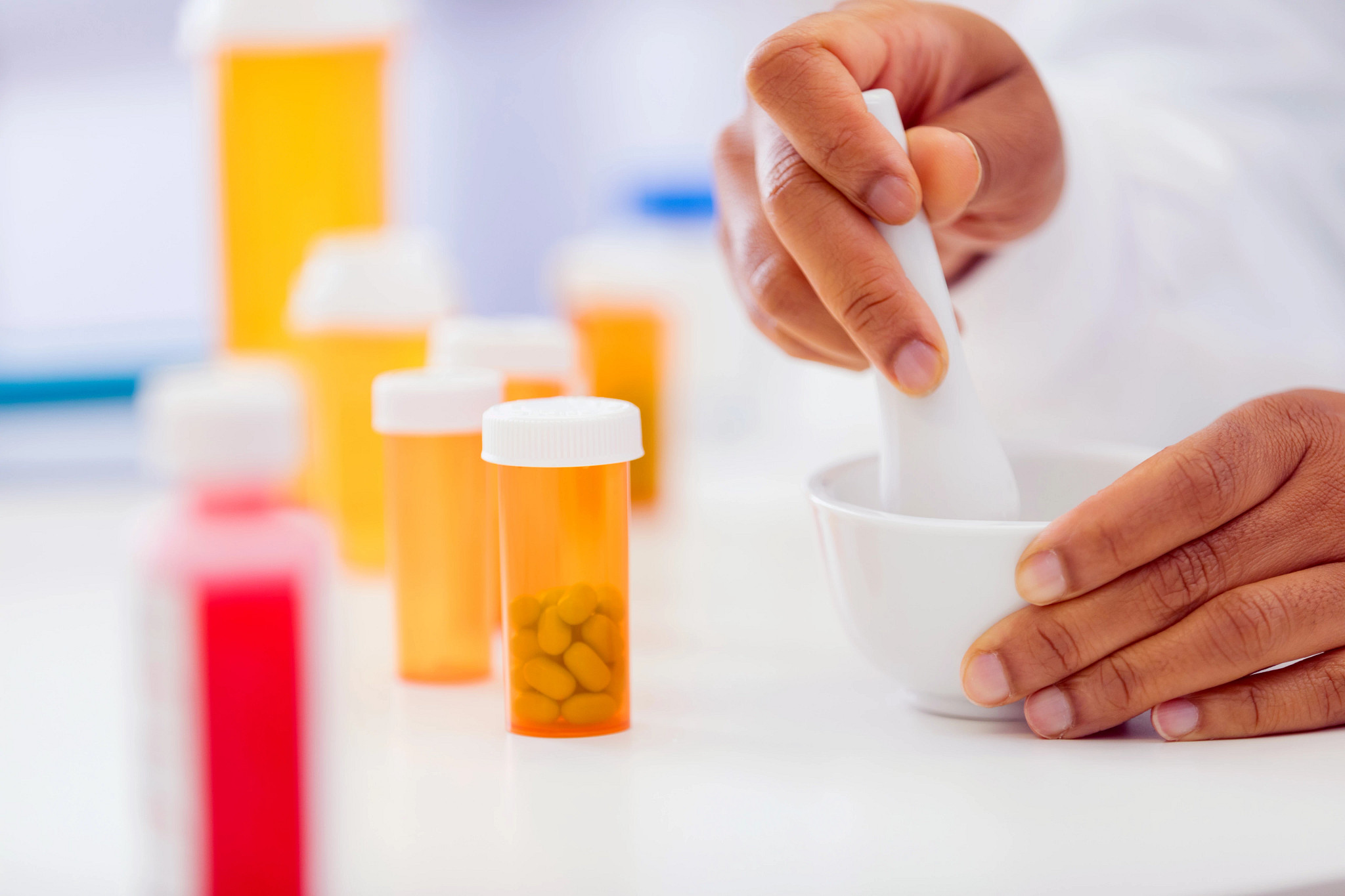 Pharmacist hands compounding prescription medication with a mortar and pestle.