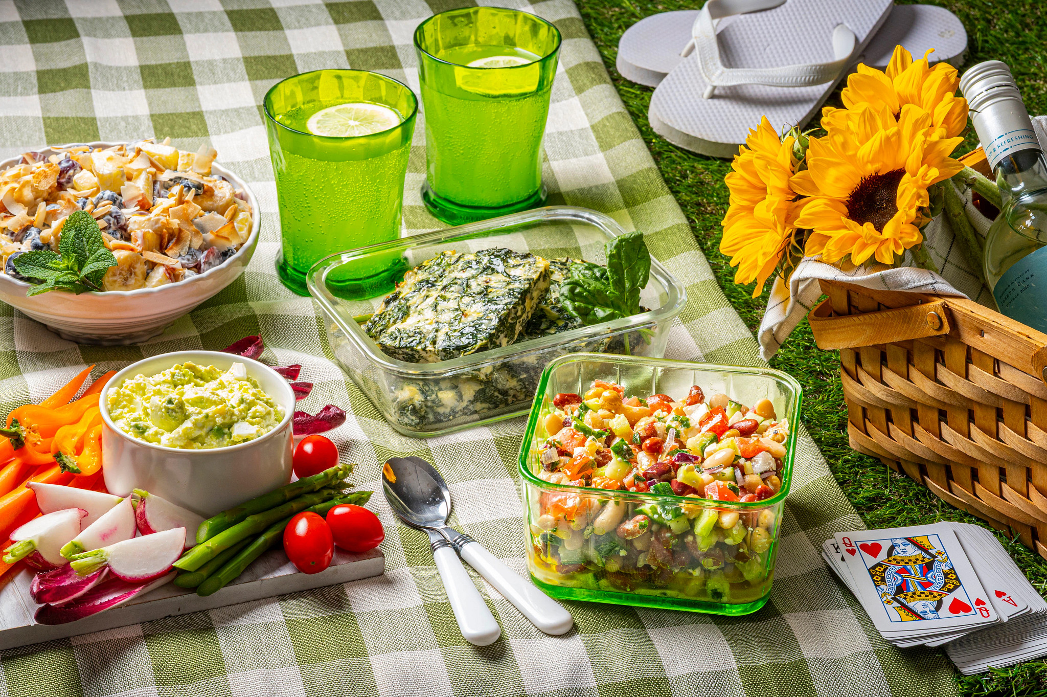 Healthy summer picnic setup featuring food on a checkered blanket