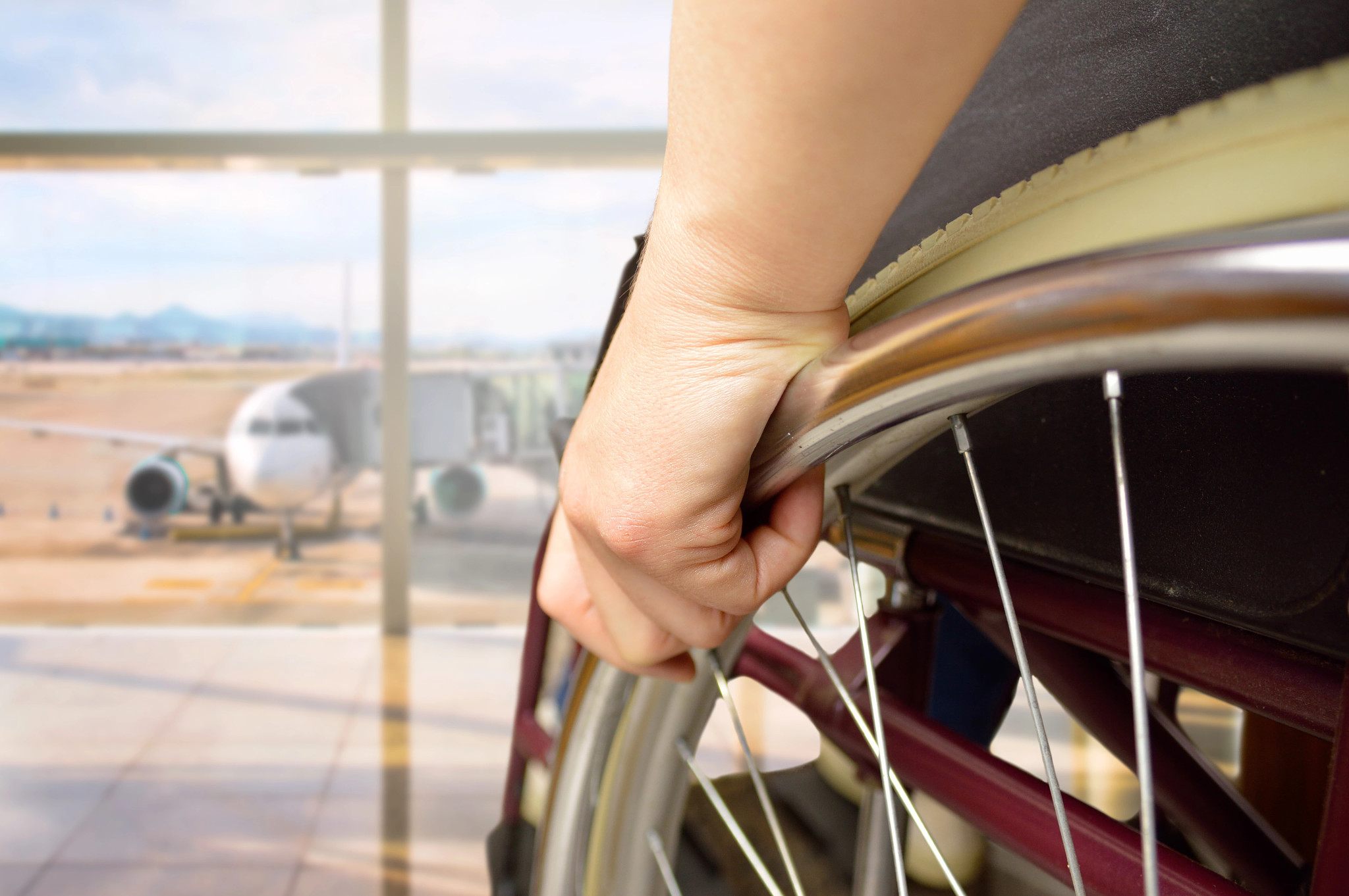 rear view of a woman in wheelchair at the airport with focus on hand