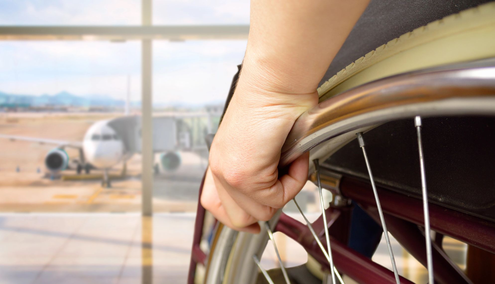 rear view of a woman in wheelchair at the airport with focus on hand