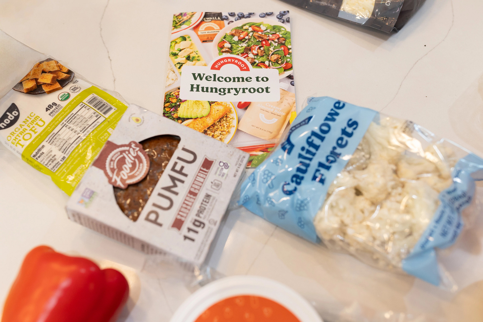 The Hungryroot welcome booklet with food around it.
