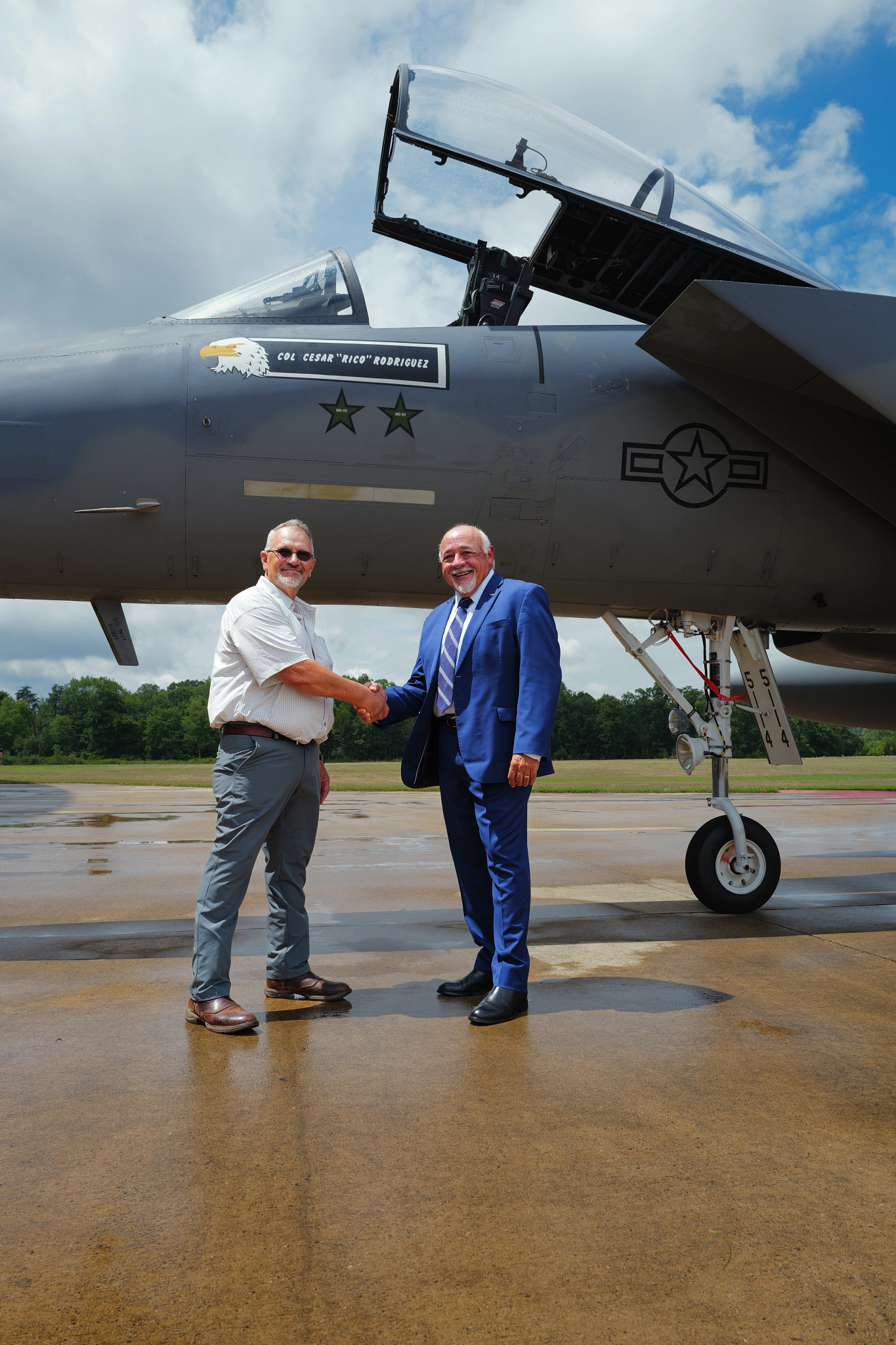cesar rodriguez and david westrop shaking hands outside a military airplane