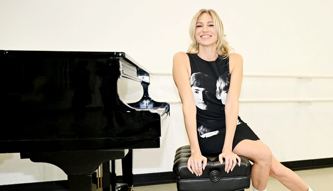Debbie Gibson Embraces Her 50s debbie gibson smiling while sitting on a piano bench next to a black piano