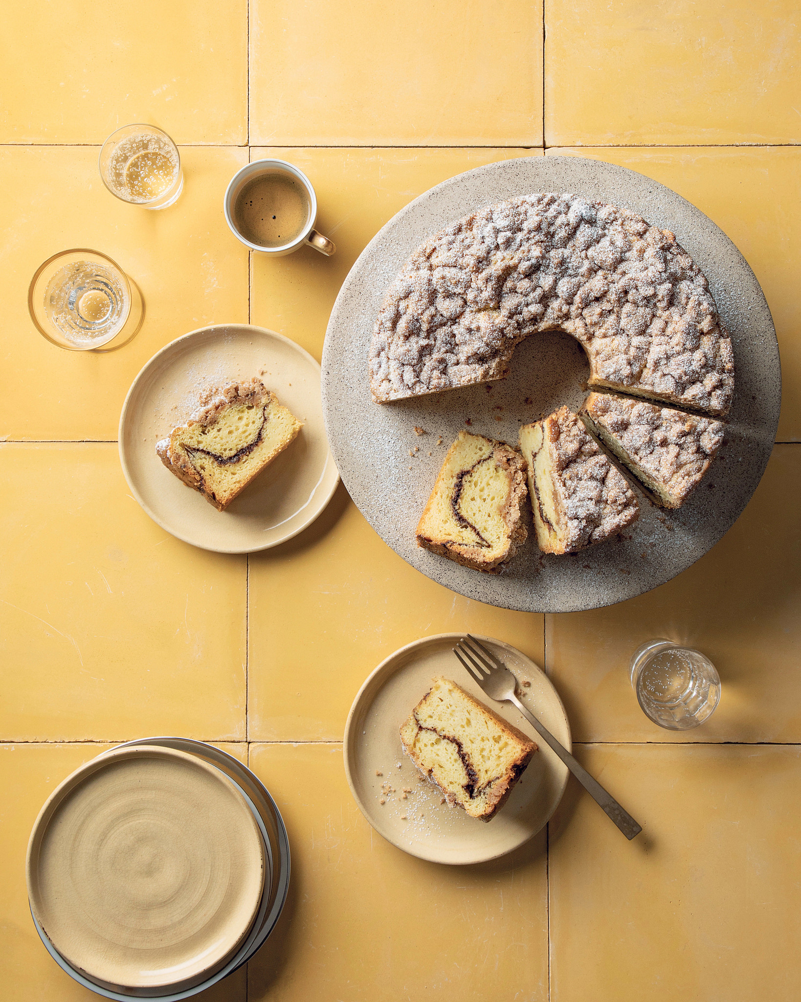 Coffee cake on dish with some slices cut; two slices on plates