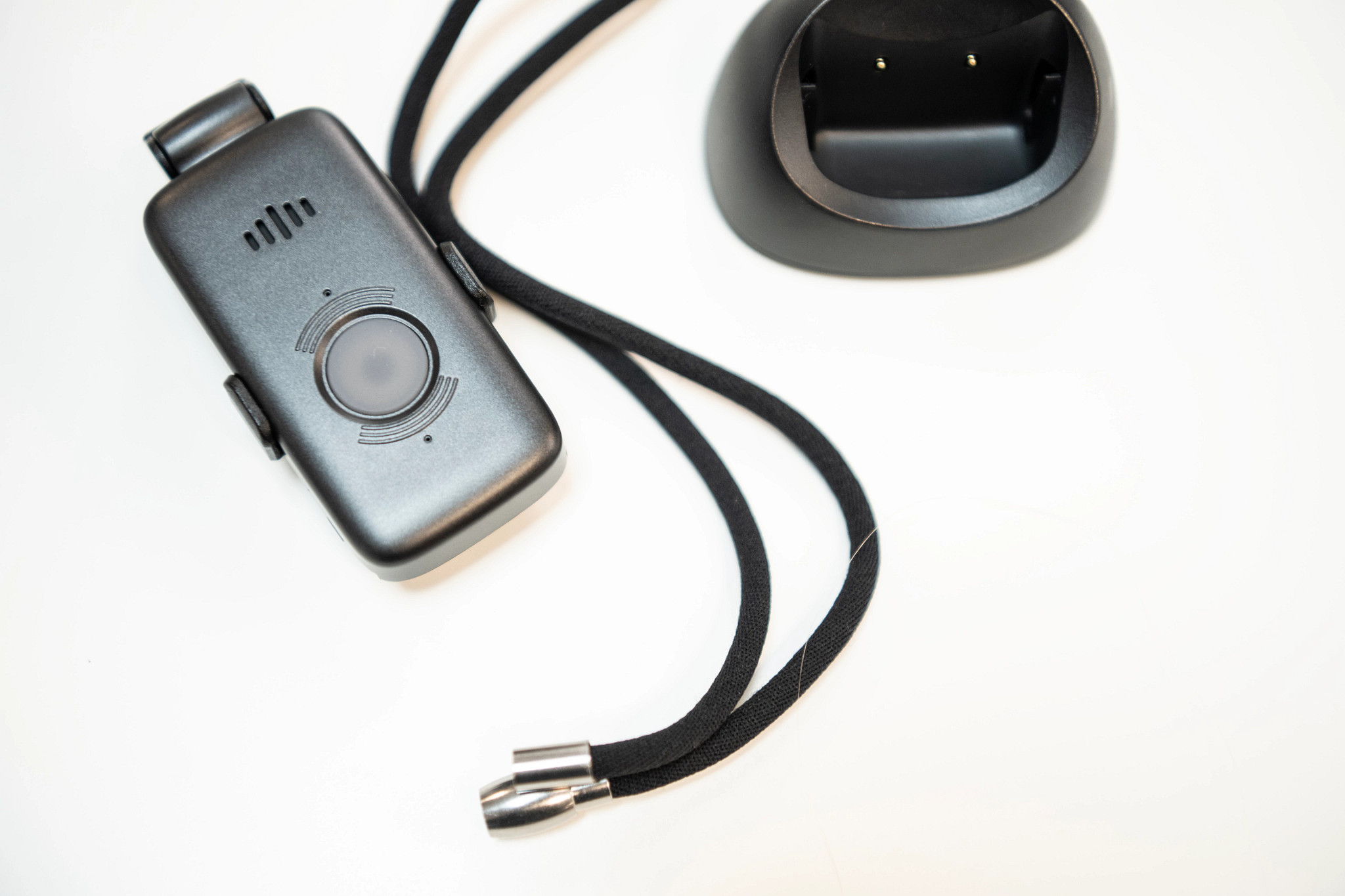 The Lifefone VIPx2 medical alert system on a table next to the lanyard and charging dock