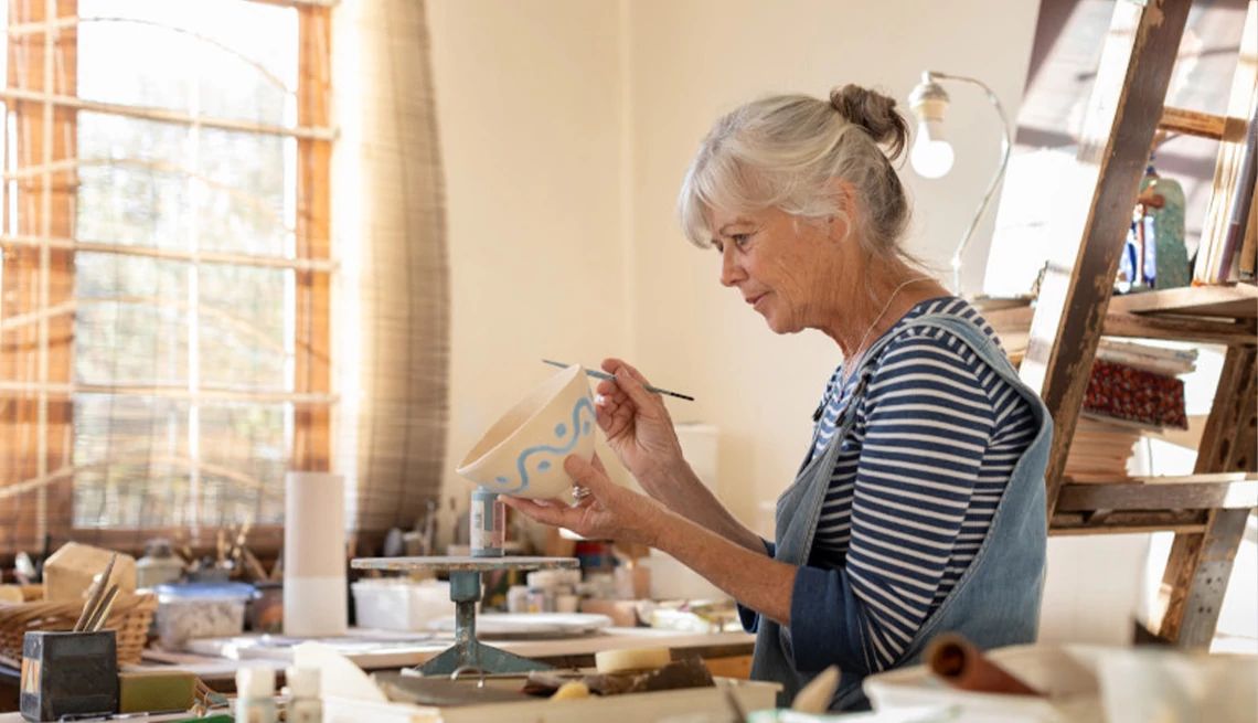 Woman painting pottery in her studio