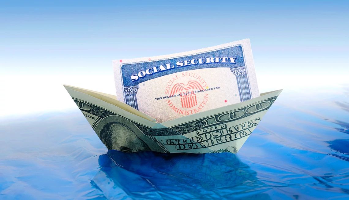 Tarjeta del Seguro Social dentro de un barco con un billete de dólar flotando sobre un fondo azul