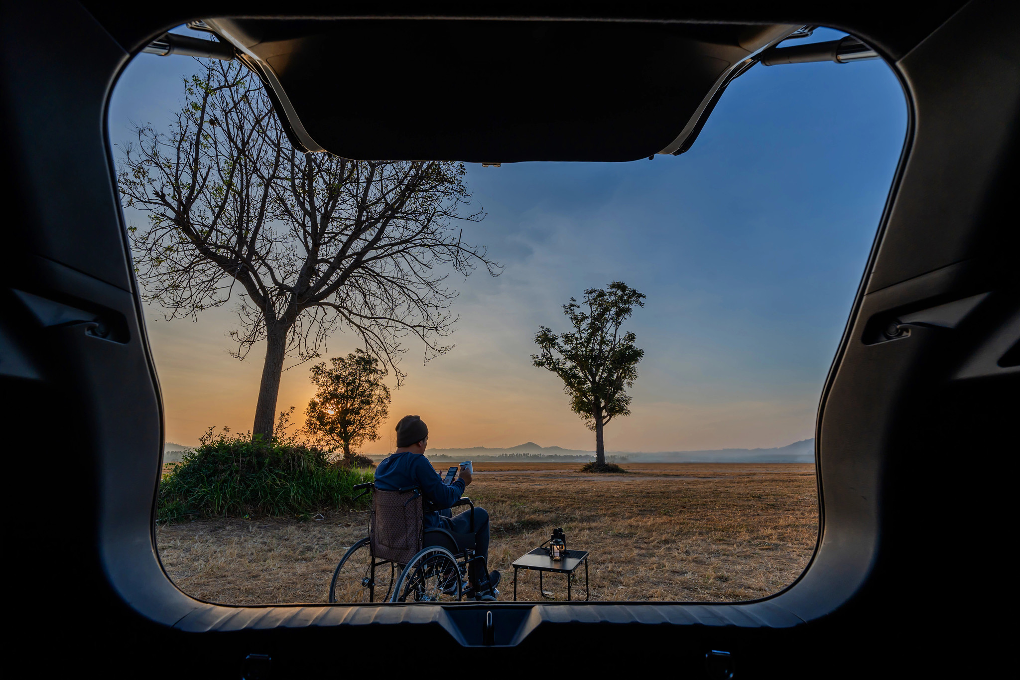 Man sitting on wheelchair with first golden sunrise of the day