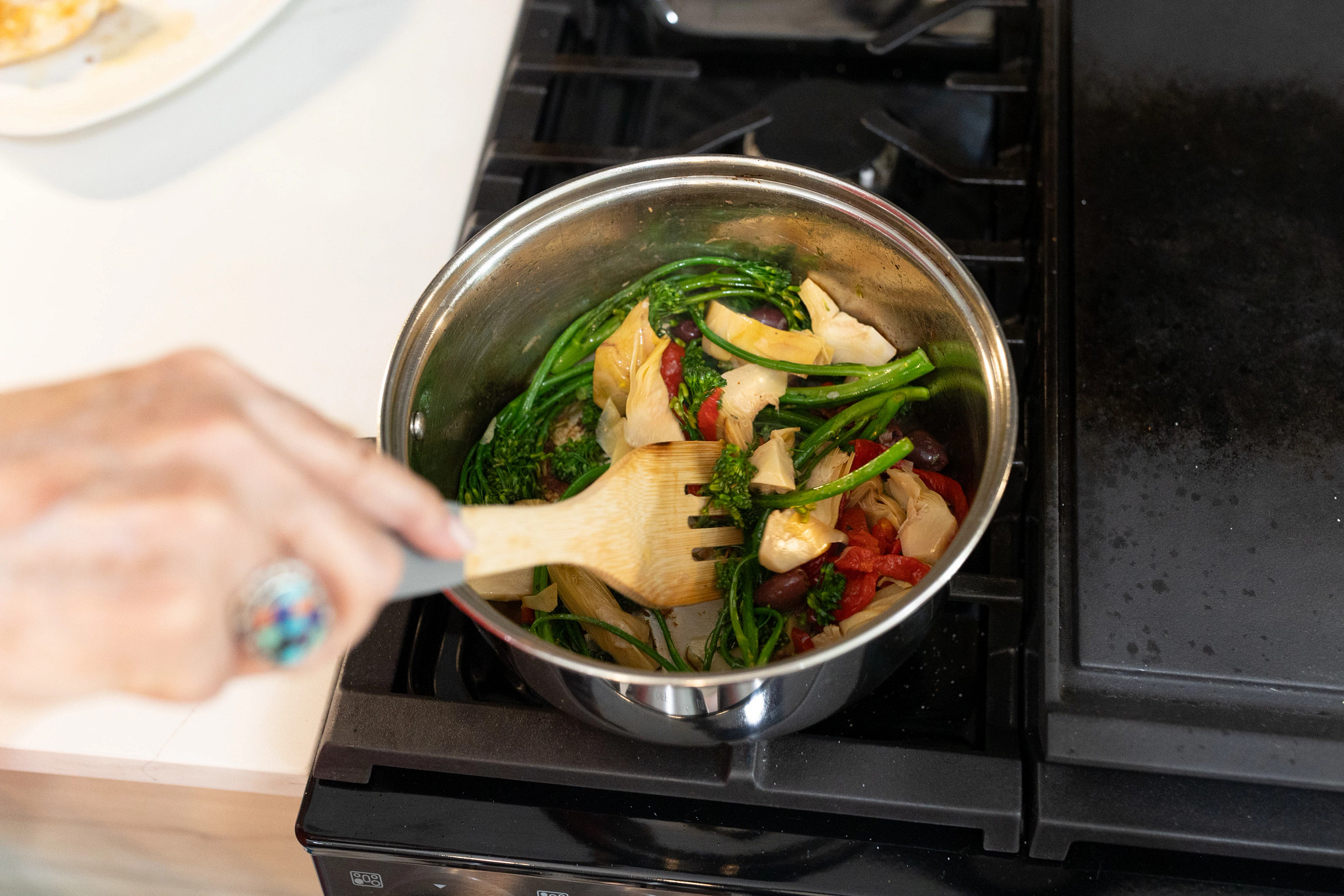 An older adult woman cooking the ingredients of her chicken and vegetable meal from Sunbasket.