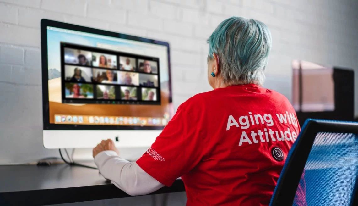 una mujer sentada en la computadora usando Senior Planet de AARP