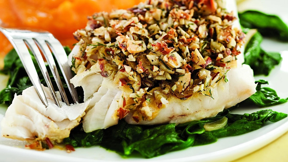 A close-up view of almond-and-lemon-crusted fish with spinach