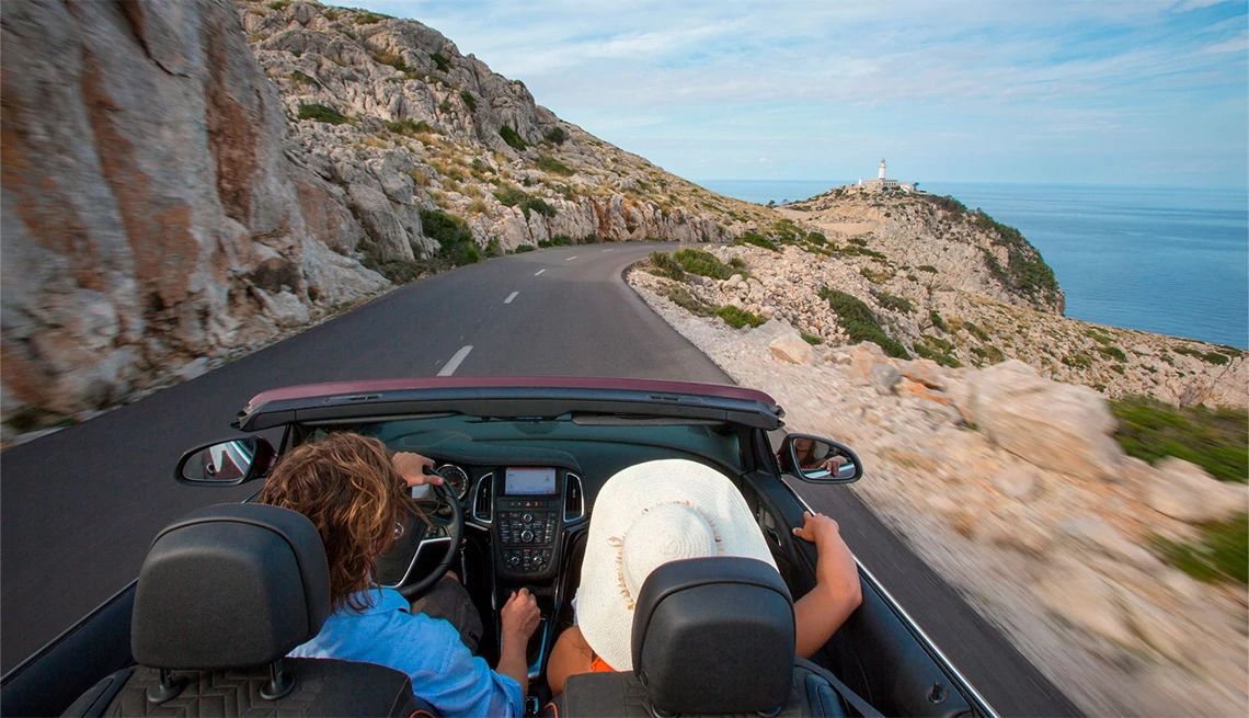 Budget Couple driving on the coast in Spain in their convertable