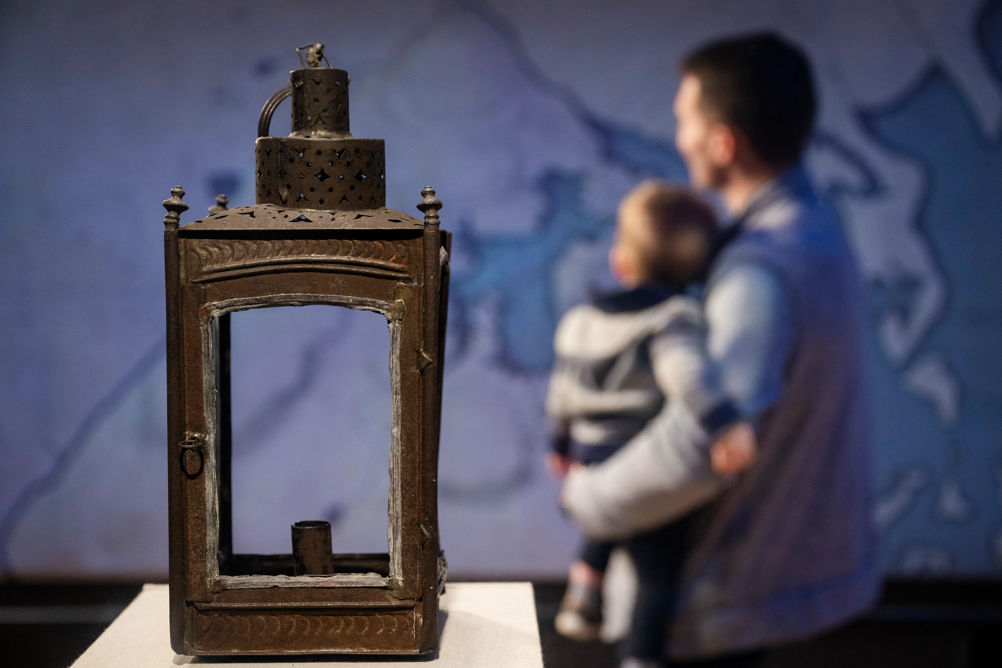 a lantern sits in the foreground with a father and child in the background